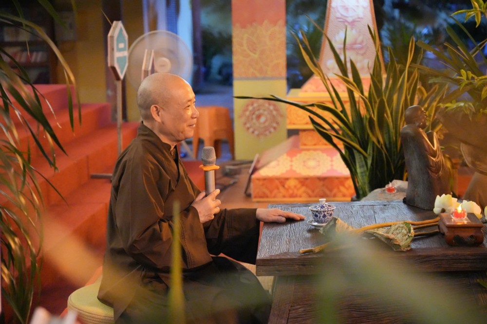 A person sitting at a table holding a microphone

AI-generated content may be incorrect.